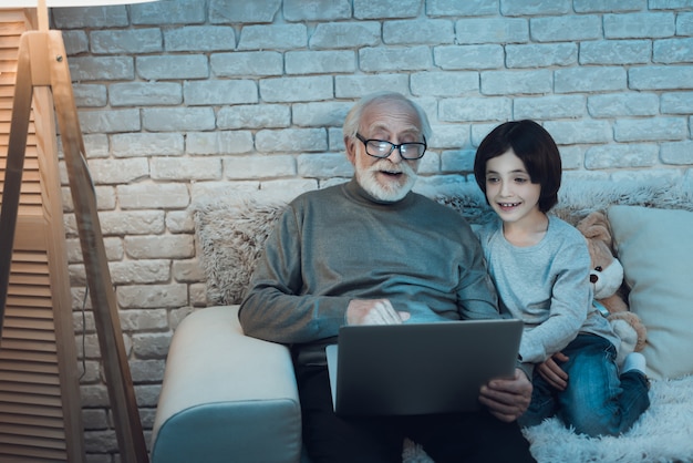 Nonno e nipote che per mezzo del computer portatile insieme