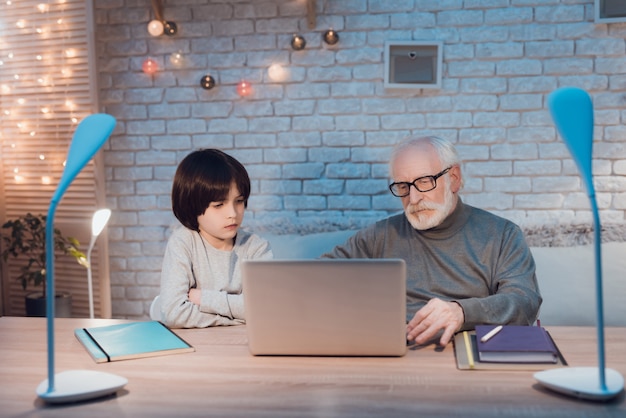 Nonno e nipote che per mezzo del computer portatile insieme