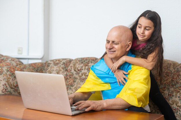 Nonno e nipote con laptop e bandiera dell'Ucraina