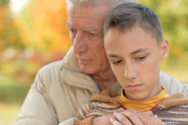 Nonno e nipote tristi che si abbracciano nel parco