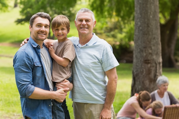 Nonno, padre e figlio con la famiglia in fondo al parco