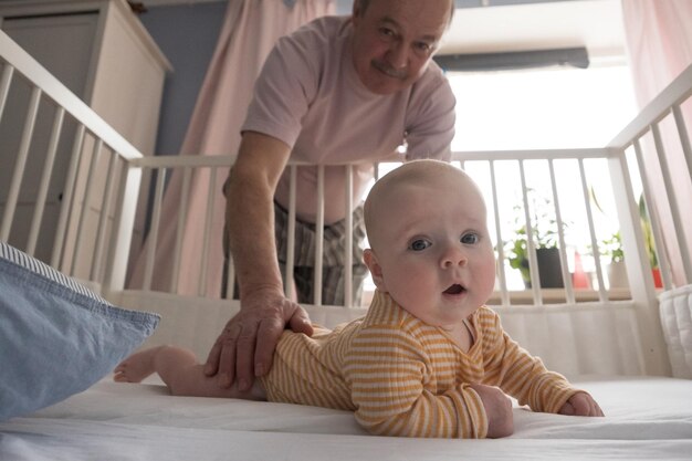 Nonno senior allegro che gioca con il nipote in camera da letto