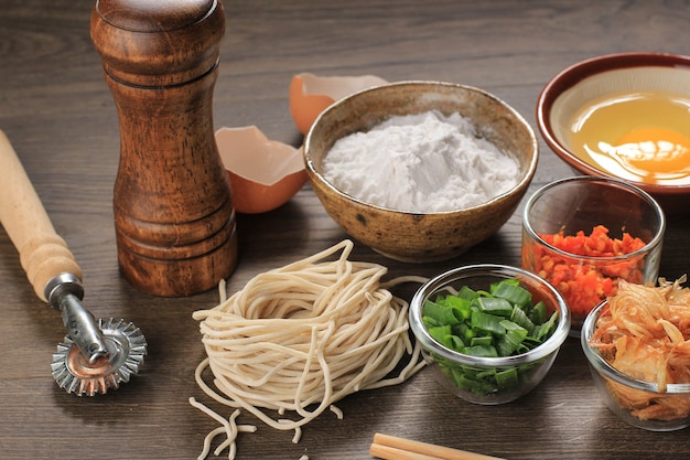 Noodle fatti in casa asiatici crudi con uova, sale, guscio d'uovo e farina, spazio copia per carta da parati o sfondi