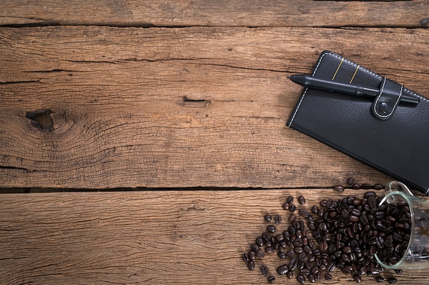Notebook e tazza di caffè in grani posti su un tavolo in legno vista dall'alto