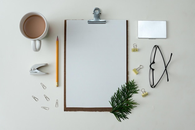 Notebook piatto su sfondo bianco con foglie estive e altri articoli di cancelleria in stile trendy