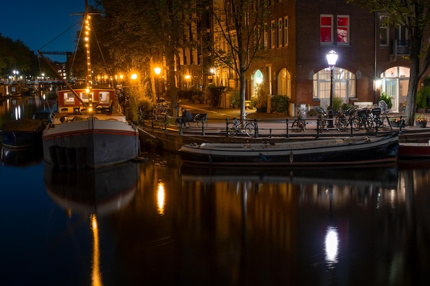 Notte Amsterdam Quay con case galleggianti e biciclette