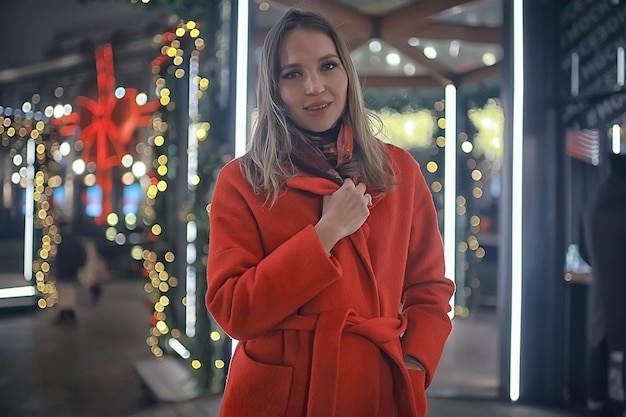 notte d'inverno nelle luci della città / ragazza adulta con un cappotto a piedi in città, immagine alla moda ed elegante di un bellissimo modello