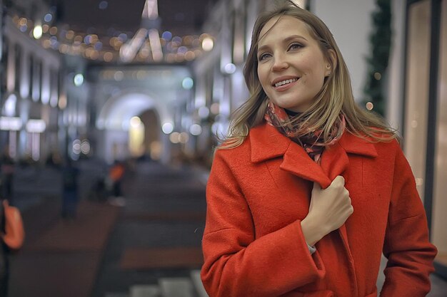 notte d'inverno nelle luci della città / ragazza adulta con un cappotto a piedi in città, immagine alla moda ed elegante di un bellissimo modello