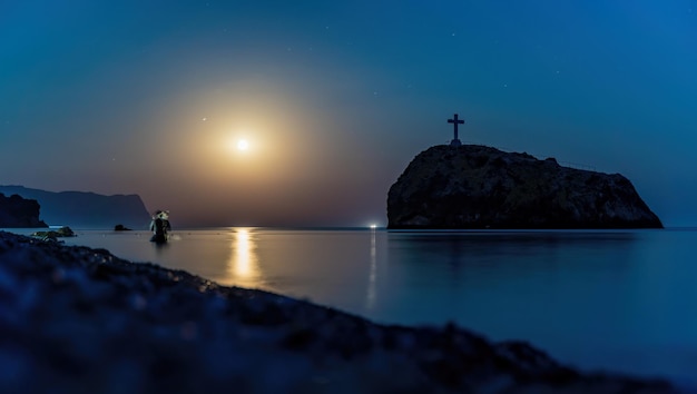 Notte stellata con luna piena sul mare con scoglio davanti capo fiolent spiaggia di diaspro roccia del santo