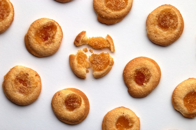 Nove biscotti fatti a mano con marmellata di albicocche disposti in file regolari da un angolo. isolato su sfondo bianco