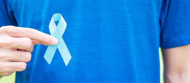 Novembre Mese di consapevolezza del cancro alla prostata, uomo in maglietta blu con mano che tiene il nastro blu per sostenere le persone che vivono e le malattie. Sanità, uomini internazionali, padre e concetto di giornata mondiale del cancro