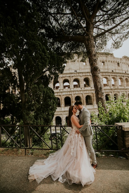 Nozze dello sposo e della sposa che posano davanti a Colosseum, Roma, Italia