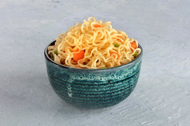 Nudle istantanee con carota e cipolle, ciotola di soba vegetale su uno sfondo di ardesia