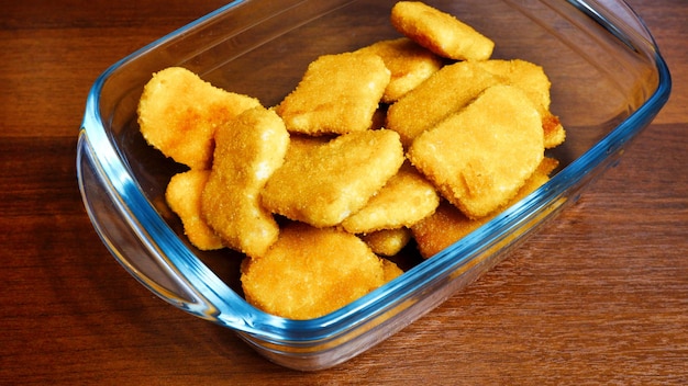 Nuggets di pollo fritto in una ciotola trasparente sul tavolo