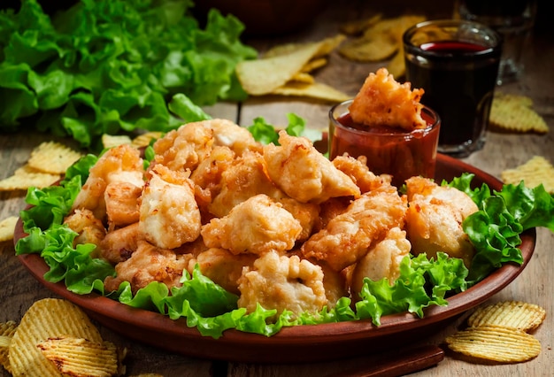 Nuggets tempura di pollo con insalata verde e salsa di pomodoro su un fuoco selettivo piatto di argilla