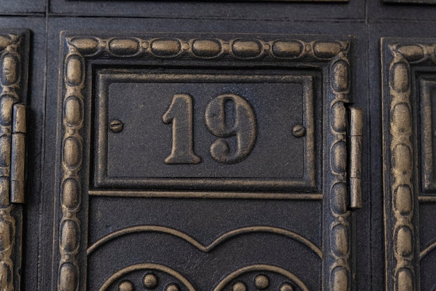 Numero 19 sulla porta di metallo Vecchia lastra di rame vintage retrò con il numero diciannove Cassette postali antiche