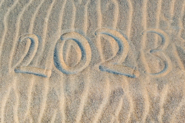 Numero 2023 scritto sulla sabbia della spiaggia tropicale