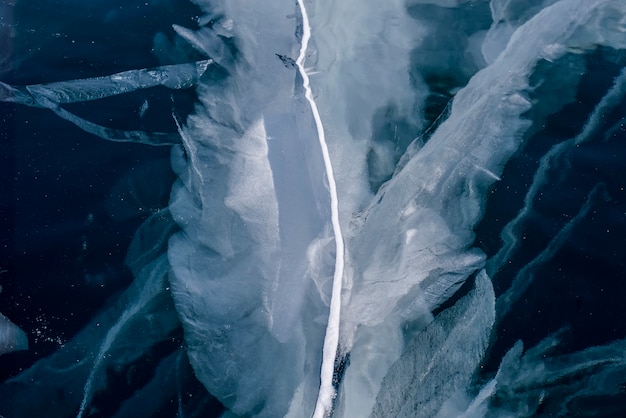 Numerose strisce di crepe nel ghiaccio trasparente blu chiaro. Orizzontalmente.