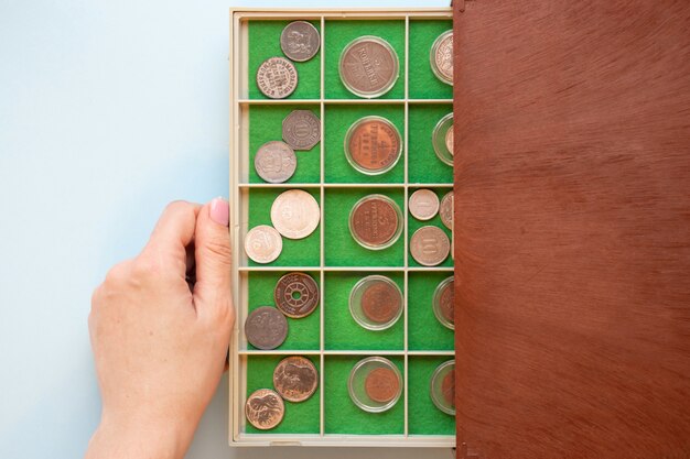 Numismatica La mano della donna tira fuori una custodia di plastica da una scatola di legno vecchie monete antiche rare e costose