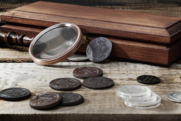 Numismatica. Vecchie monete da collezione su un tavolo di legno. Sfondo scuro.