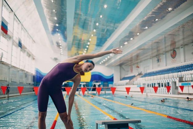 Nuotatore di giovane donna in fase di riscaldamento prima di nuotare in piscina