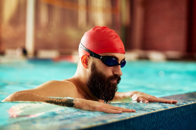 Nuotatore in piedi sul trampolino pronto a tuffarsi nella piscina da competizione