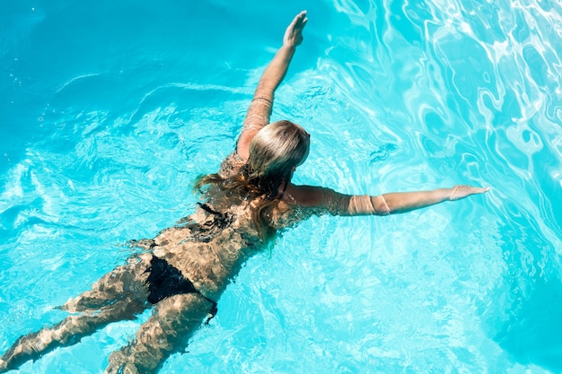Nuoto adatto della donna nello stagno in un giorno soleggiato