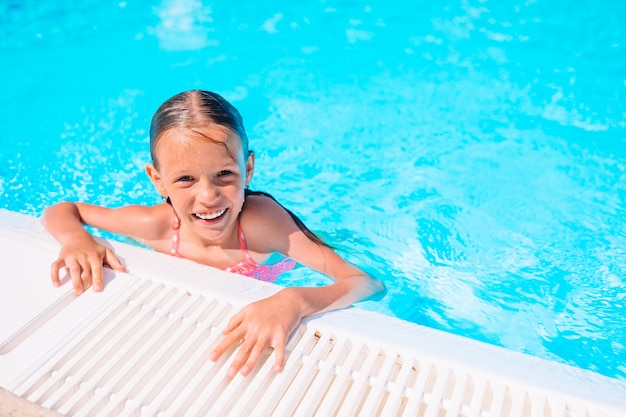 Nuoto adorabile della bambina alla piscina all'aperto