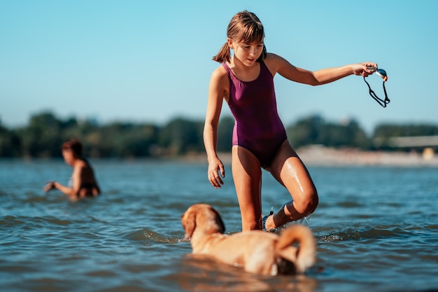 Nuoto della ragazza nel fiume con il suo cane