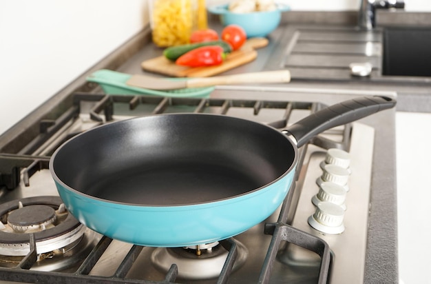 Nuova padella sul fuoco Le verdure fresche si trovano vicino alla padella sul piano di lavoro