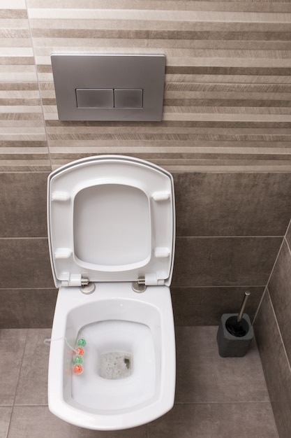 Nuova toilette in ceramica bianca su uno sfondo di piastrelle grigie. L'interno del bagno. Stile moderno.