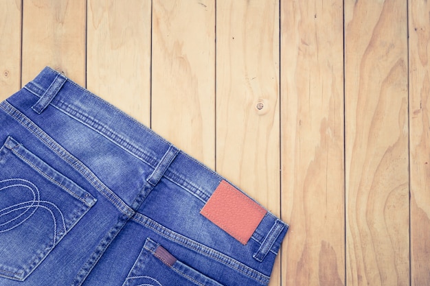 Nuove blue jeans sulla vista superiore del fondo di legno