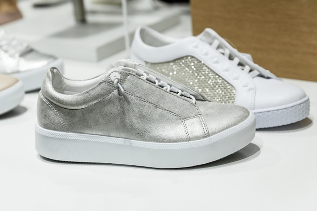 Nuove sneakers casual in pelle argento con suola bianca su uno scaffale di un negozio Calzature street urban