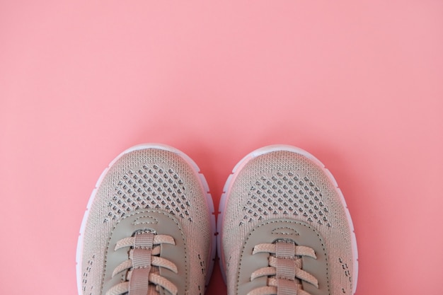 Nuove sneakers grigie su sfondo rosa pastello