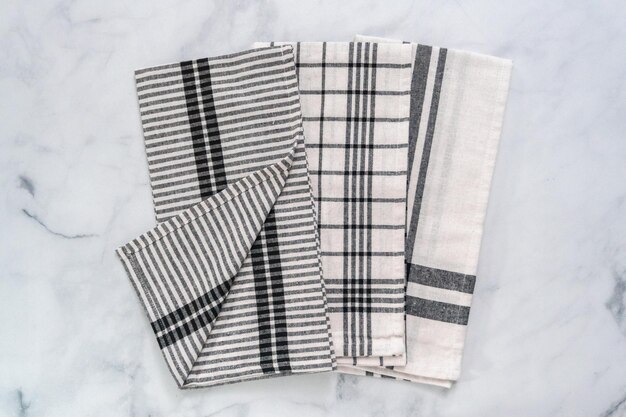 Nuovi asciugamani da cucina con semplice motivo nero piegati su bancone in marmo.