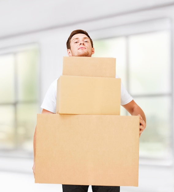 nuovo concetto di consegna a casa e dopo la consegna - giovane uomo che trasporta scatole di cartone
