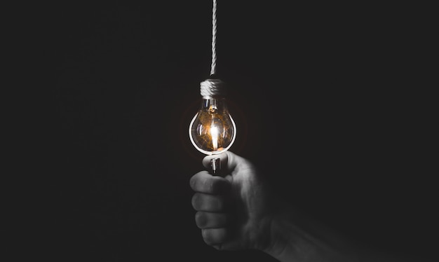 Nuovo concetto di idea. L'uomo tiene in mano un alleggerimento vicino alla lampadina. Foto in bianco e nero.