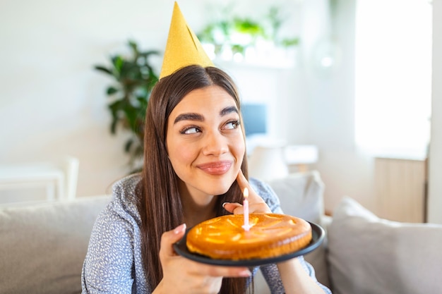 Nuovo concetto normale. Donna felice che festeggia il suo compleanno da sola. giovane donna che tiene una torta. Festa di compleanno a casa. Videochiamata familiare. Riduzione dei contatti. Vita a casa.