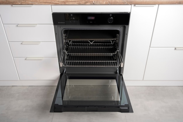 Nuovo forno elettrico moderno costruito in nero con schermo, convenzione e grill, vuoto e aperto.