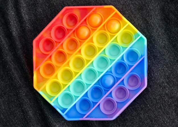 Nuovo popolare giocattolo antistress colorato in silicone pop it per bambini su sfondo nero Vista dall'alto Spazio di copia Semplice fossetta