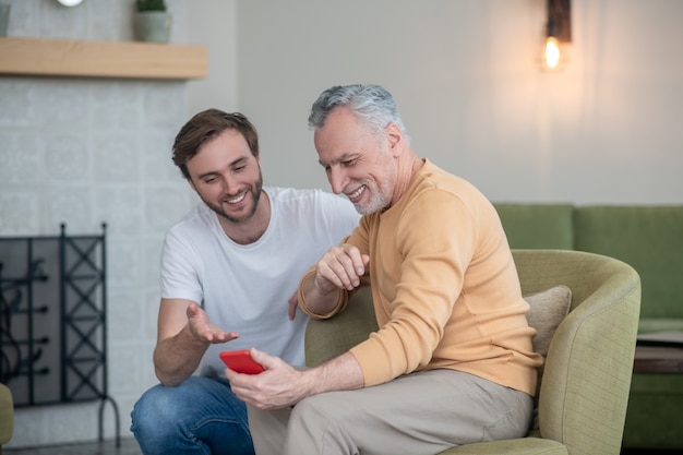 Nuovo smartphone. Giovane che spiega a suo padre come usare un nuovo smartphone