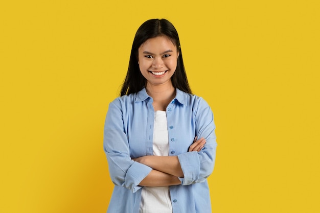 Nuovo stile e successo Felice studentessa coreana millenaria fiduciosa in casual con le braccia incrociate guarda la macchina fotografica