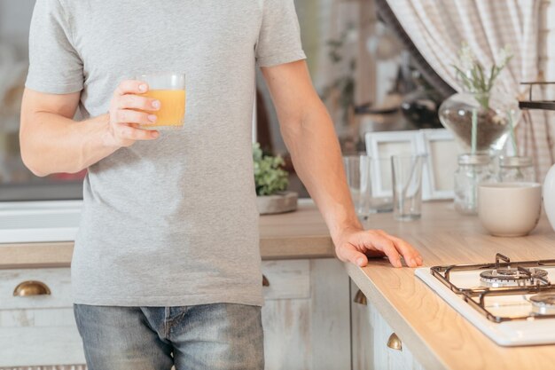 Nutrizione equilibrata Immagine ritagliata di un uomo in piedi in cucina con un bicchiere di succo d'arancia biologico fresco Sfocatura dello sfondo