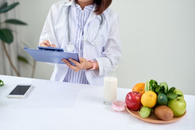 Nutrizionista femminile con frutta che lavora alla sua scrivania