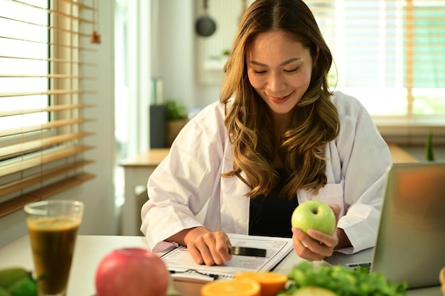 Nutrizionista professionista che lavora su un piano dietetico seduto con diversi ingredienti alimentari sani in ufficio Nutrizione corretta alimentazione sana