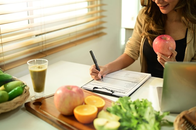 Nutrizionista seduto alla scrivania con frutta e verdura che lavora sul piano dietetico Mangiare sano giusto concetto di nutrizione e dieta