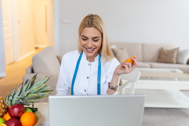 Nutrizionista sorridente nel suo ufficio sta mostrando frutta e verdura sane concetto di assistenza sanitaria e dieta Nutrizionista femminile con frutta che lavora alla sua scrivania