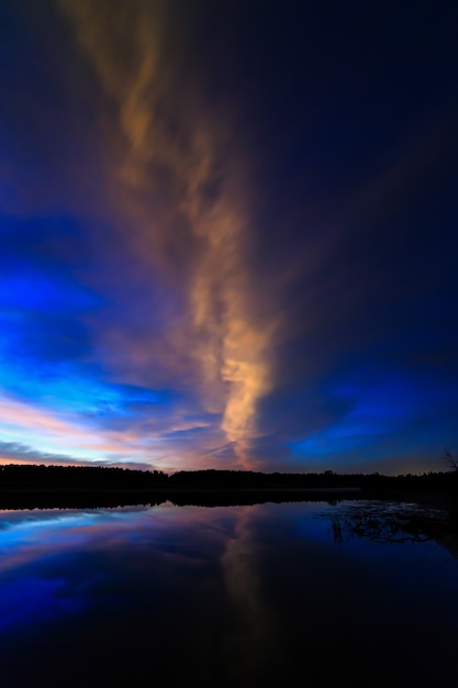 Nuvola nel cielo illuminato dall'alba mattutina, riflessa nell'acqua del lago.