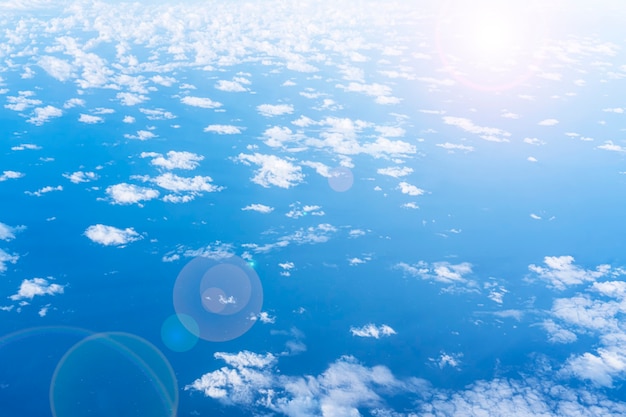 Nuvole bianche in un cielo azzurro, vista dall'oblò, vista dall'alto. bagliore solare, bellissimo sfondo blu.