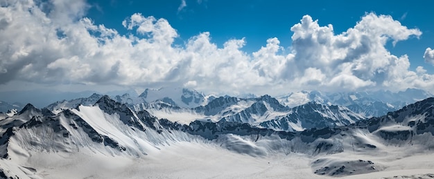 Nuvole di montagna su bellissime cime innevate di montagne e ghiacciai. Vista sulle montagne innevate.